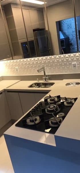 Bancada clara com cooktop e cuba, sobre marcenaria azul